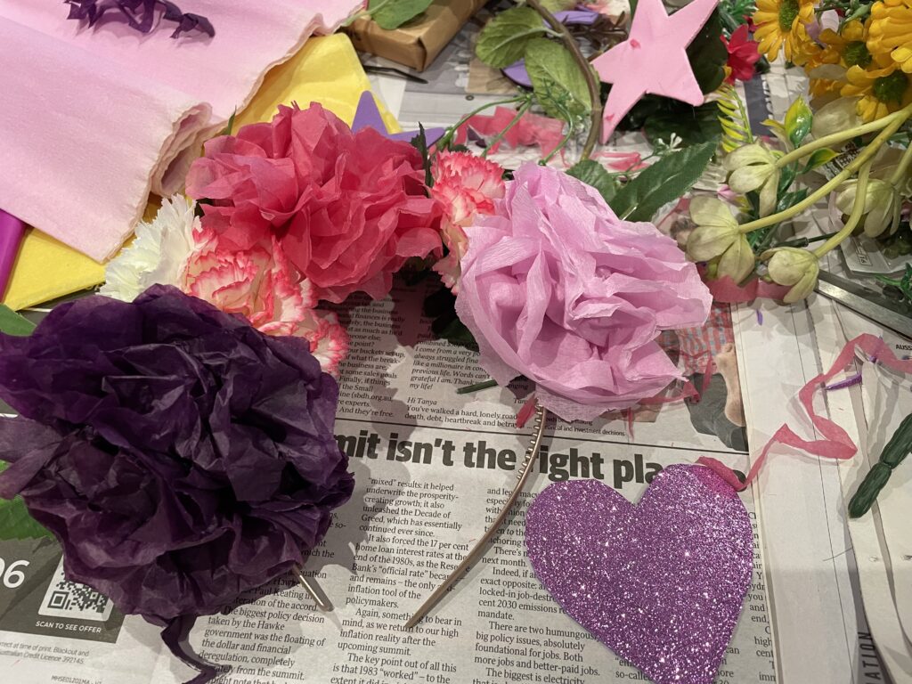 corona con flores de diferentes colores dispuestas sobre ella con un corazón de purpurina rosa recortado